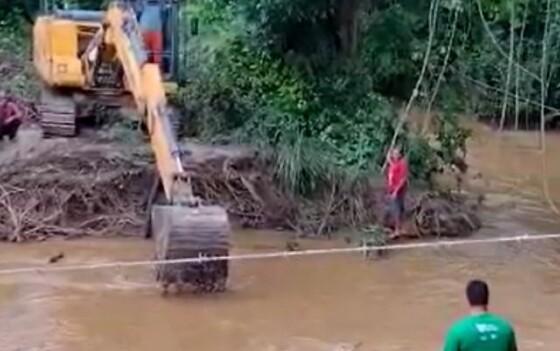 Bombeiros usam retroescavadeira para limpar rio e tentar localizar menina desaparecida após cair na água